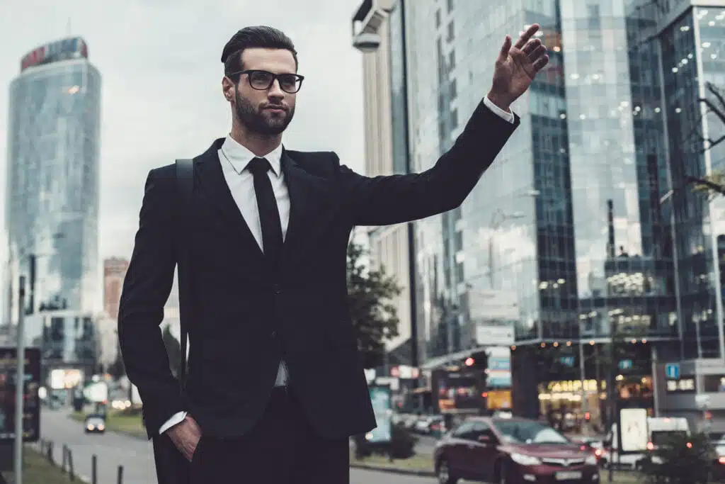 Photo illustrative d'un homme d'affaire en costume qui arrête un taxi un téléphone à la main